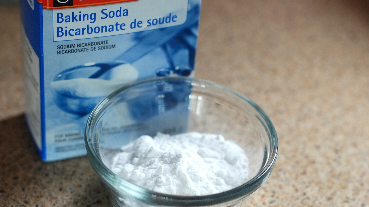 a box of baking soda and some of it in the bowl are placed on the table